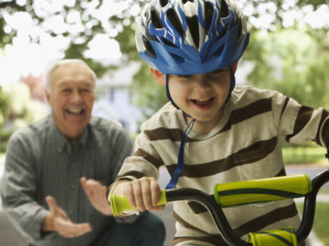 Caucasian man teaching grandson to ride a bicycle
